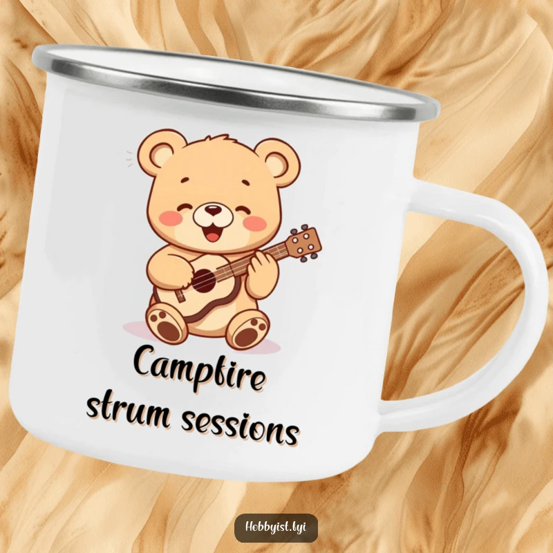 Funny bear cub playing a small ukulele, depicted on a durable enamel camping mug, ideal for outdoor adventures.