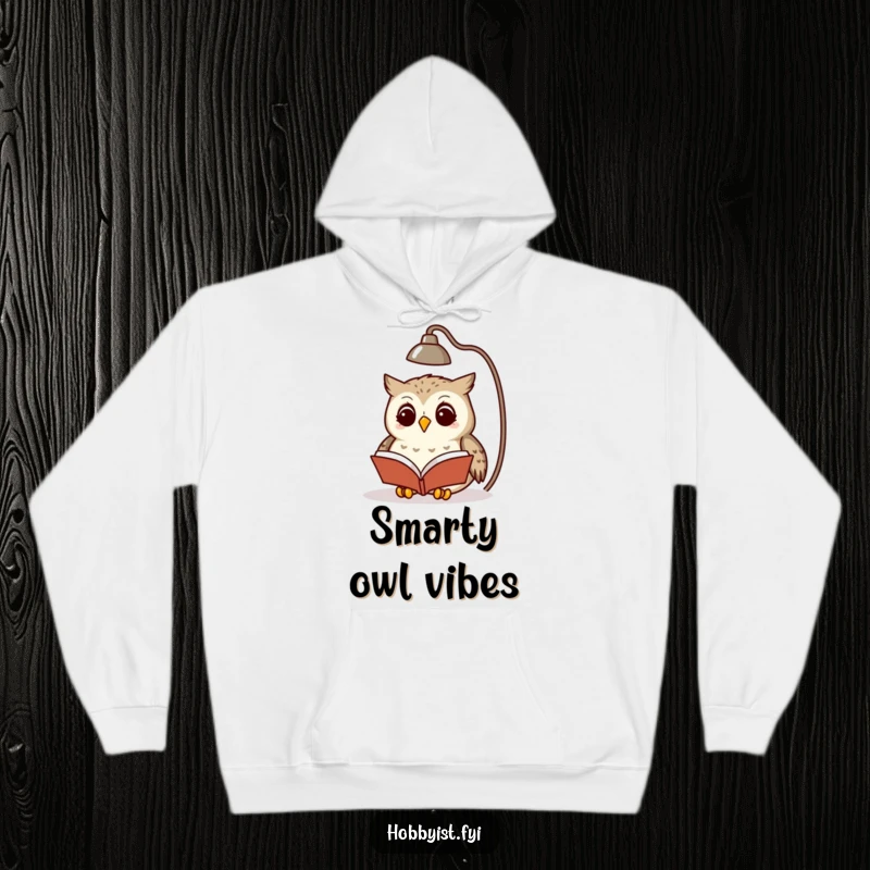Funny owl engrossed in a tiny book under a lamp, depicted on a soft hooded sweatshirt, ideal for cozy nights.